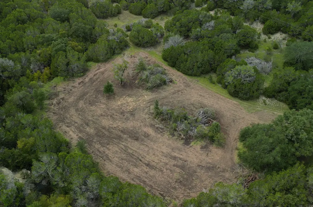 Aerial view of newly cleared acreage surrounded by mature Hill Country trees
